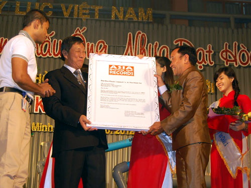 Tổng giám đốc Tổ chức Kỷ lục châu Á Biswarroop Roy Chowdhury (bìa trái) trao Bằng kỷ lục Guinness châu Á cho Giám đốc Cty Nhựa Đạt Hòa và nghệ sĩ Mai Đình Tới