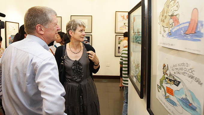 Đại sứ CHLB Đức tại Việt Nam Jutta Frasch (phải) đang chăm chú theo dõi một tác phẩm tranh biếm họa “Hướng về biển Đông” - Ảnh: Nguyễn Khánh